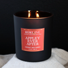 Black Appley Ever After candle with a red label on a white surface against a dark background
