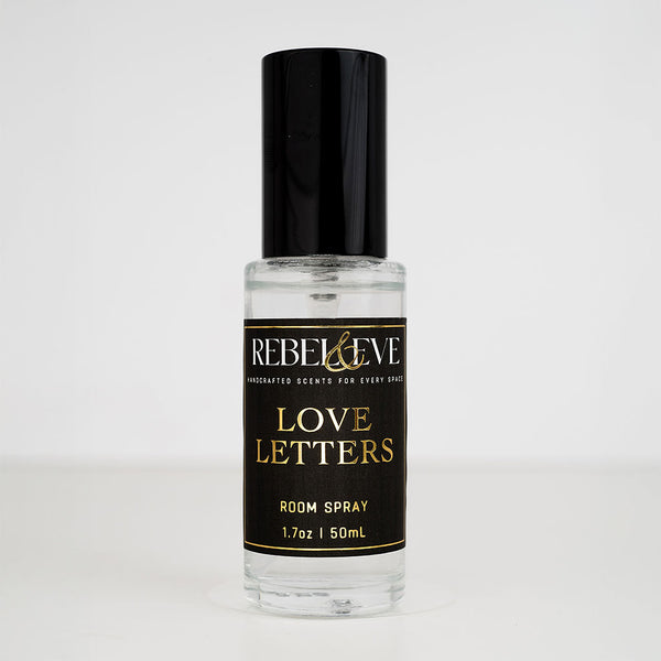 A bottle of 'Love Letters' room spray with a black cap and a label that includes the product name and the scent, peony, written in a stylish font.